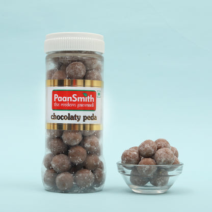 Jar of PaanSmith chocolaty peda with a small bowl of peda on a light blue background